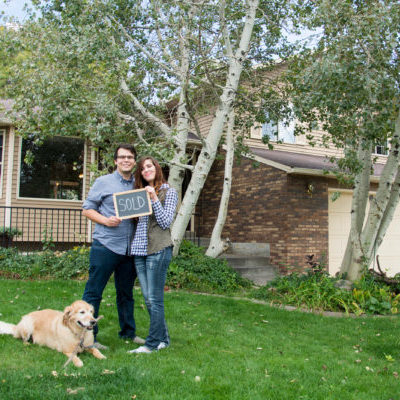 couple and dog in front of new home with sold sign